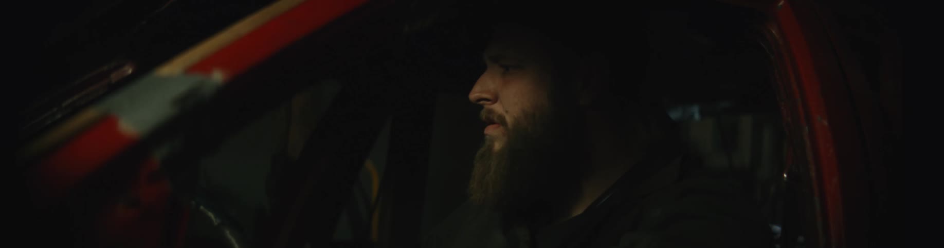 A man is sitting in a parked car at night