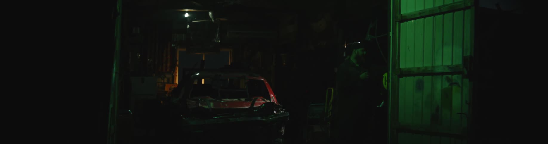 A person is standing by a car in a garage at night