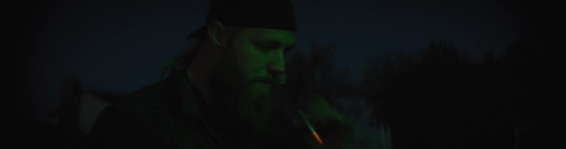A man is walking in the darkness carrying a flashlight