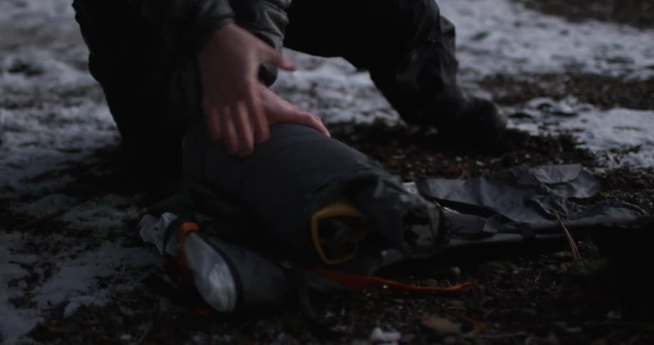 A man rolls up his camping gear