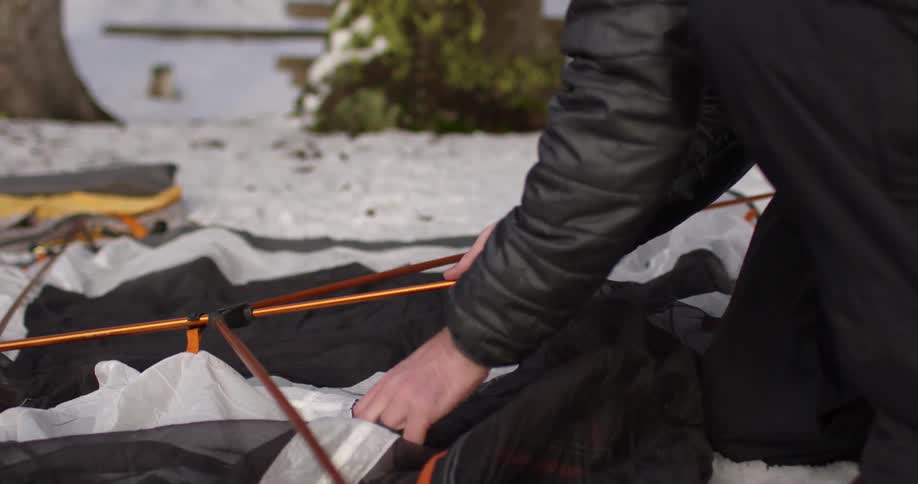 Man sets up a tent outside in the snow