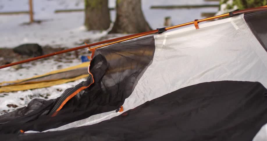 A person is setting up a tent on snow