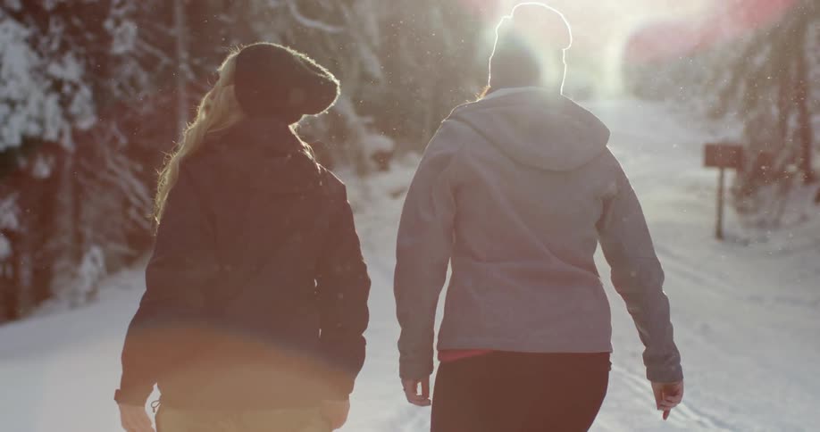 Two women walk in the snow together