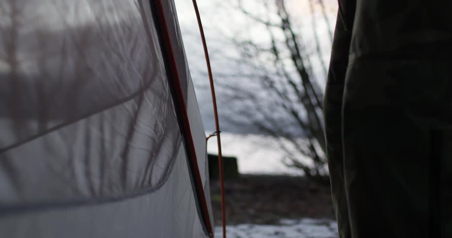 A woman closes a tent flap