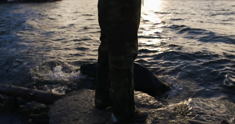 Woman walks on lakeshore rocks on a chilly day