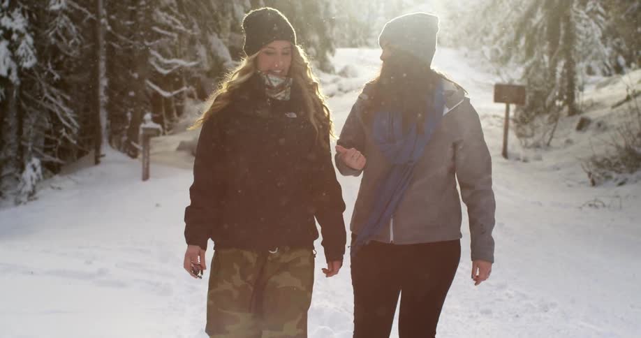 Two women talk as they walk in the snow