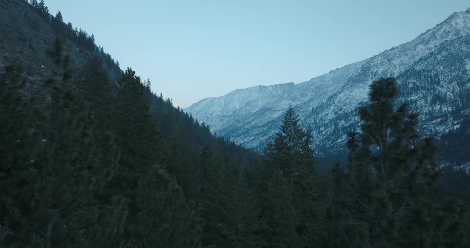 Pushing just below the tops of evergreen trees as the first snow of the season lightly covers mountains in the distance