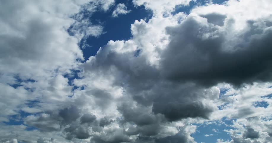 Cumulus clouds are moving across a deep blue sky