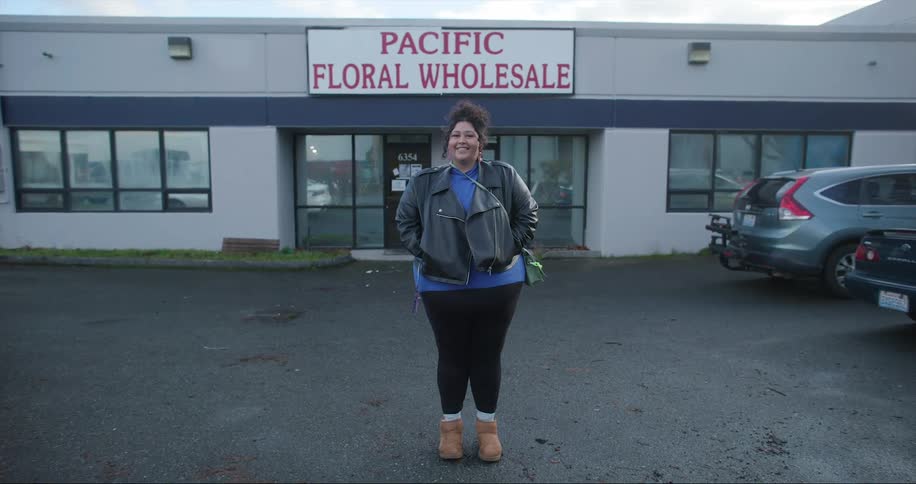 A woman smiles while posing in front of a wholesale florist business