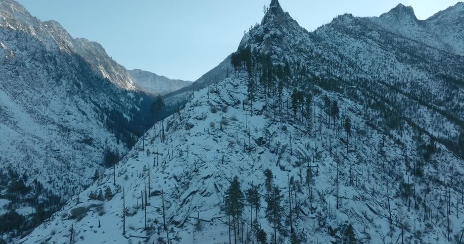 Tilt up reveal of a pointy and jagged snow covered mountain ridge