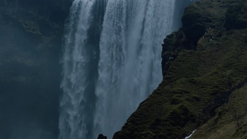 White birds sit on steep slope as waterfall flows downward nearby