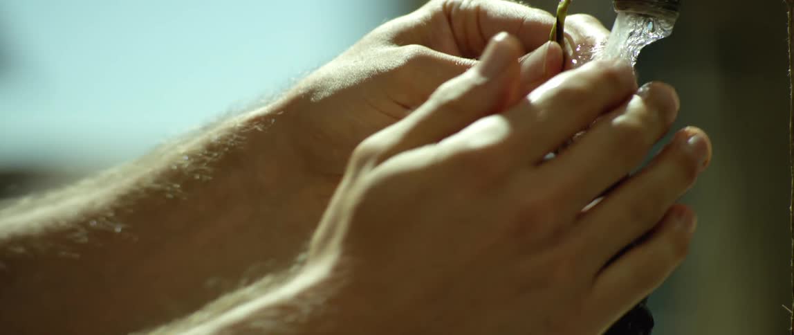 A man washes grapes under a faucet
