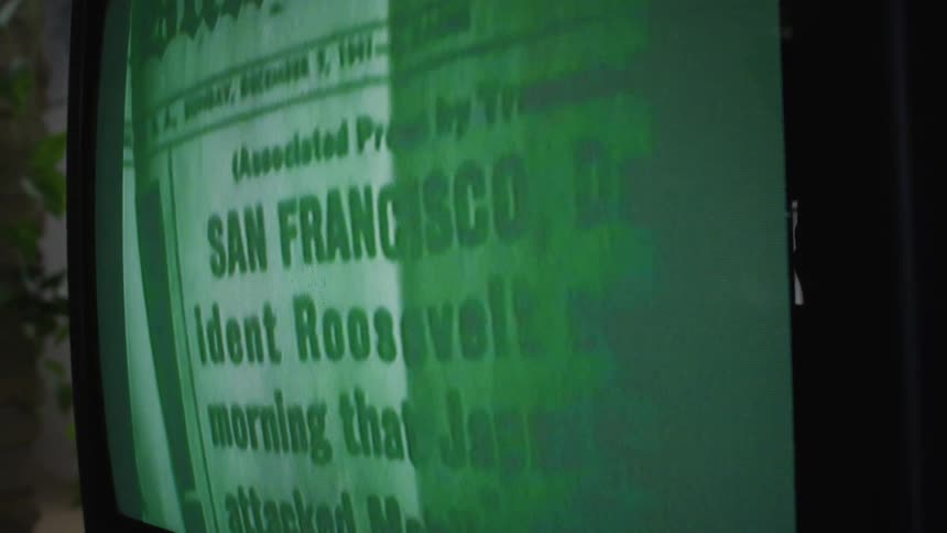 A person is holding a newspaper on the television screen