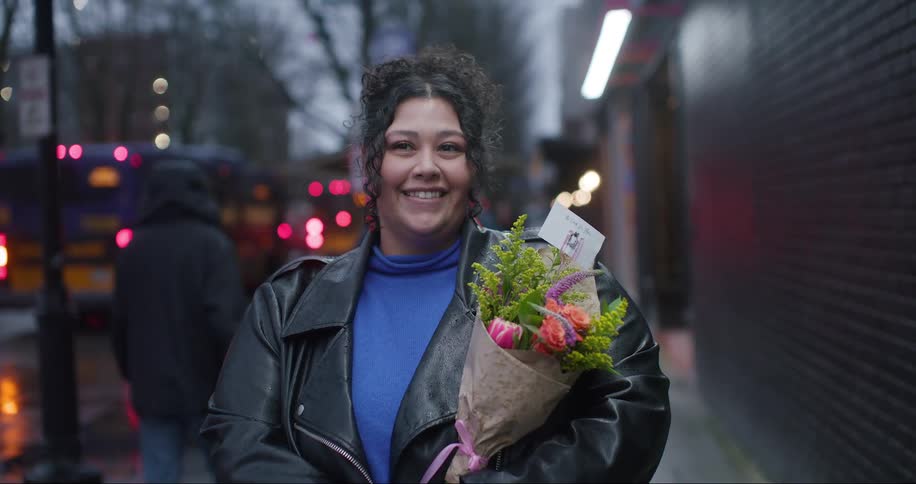 A woman standing outdoors holding flowers