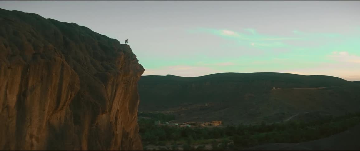 Aerial of person in the distance standing at the edge of cliff