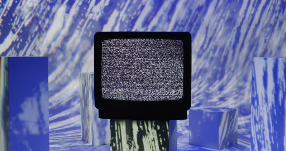 Colorful graphics project into a room where static plays on a tube style television