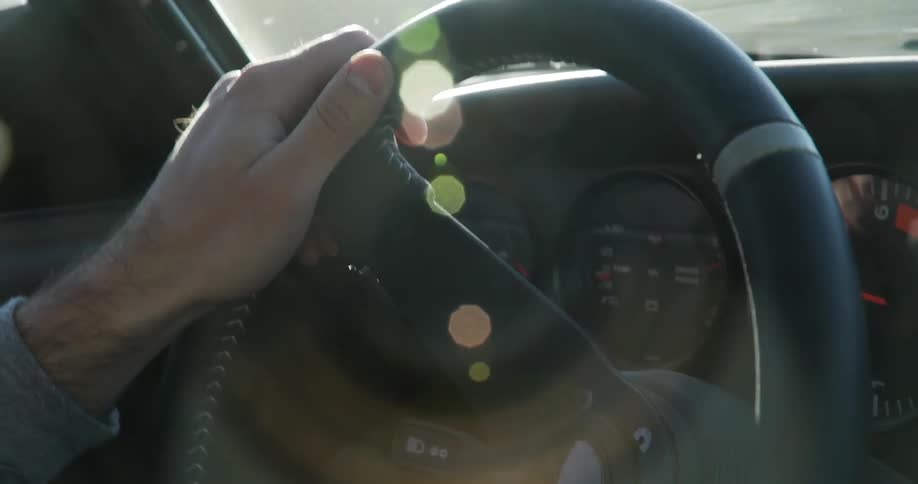 A man driving an automobile is holding the steering wheel as he navigates his vehicle