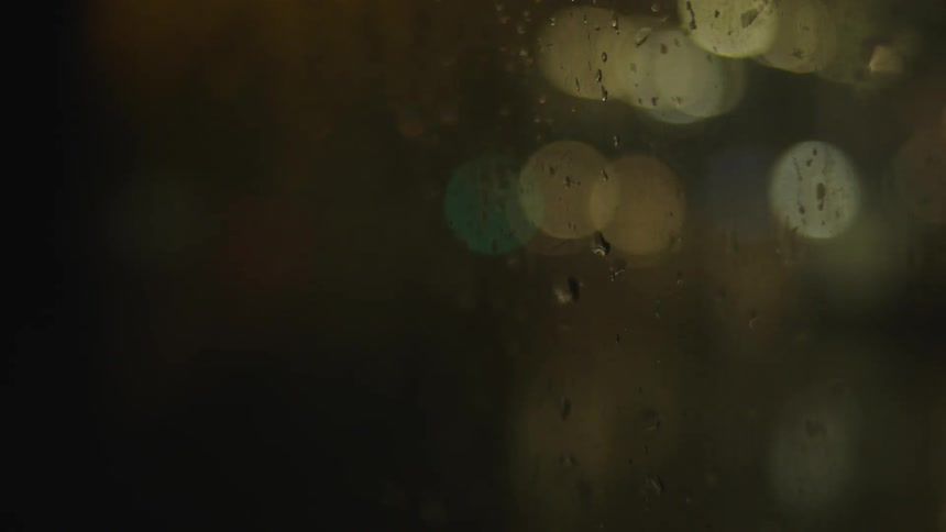 The window is blurred and covered with water