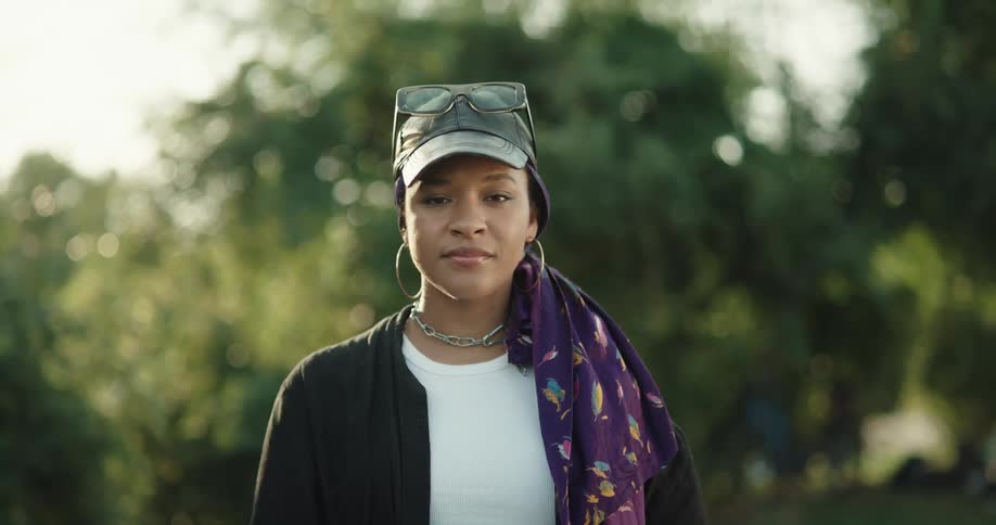 Woman wearing scarf and baseball cap stands outdoors