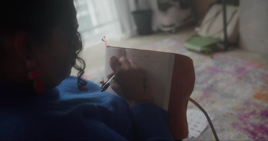 Woman sits writing in journal with a pen