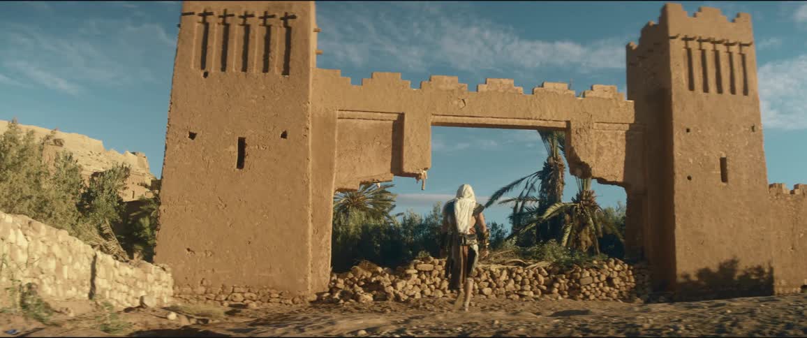 A man walks in the desert towards the ruins