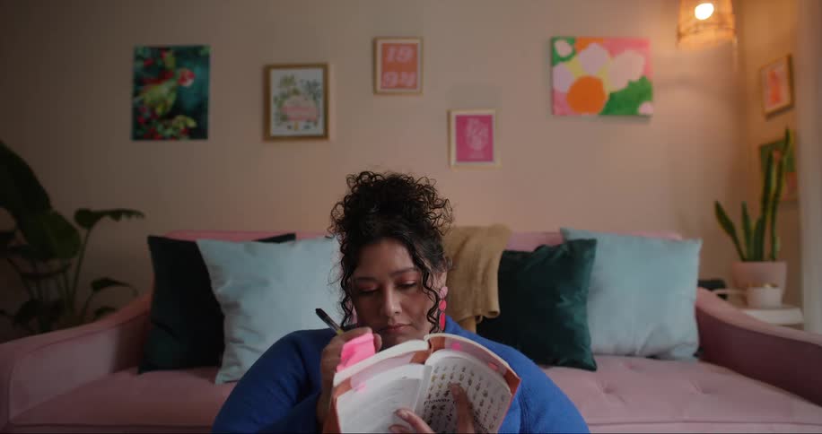 A woman sits at home and writes in a book