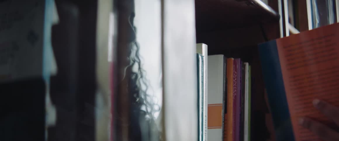 A woman takes a book off the shelf in the library