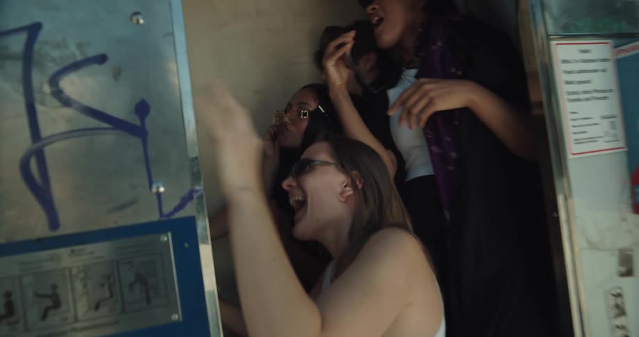 A group of friends run into a photo booth near downtown