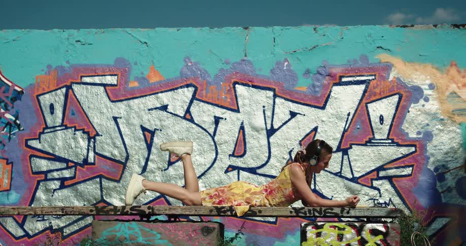 A woman is writing by the graffiti filled wall