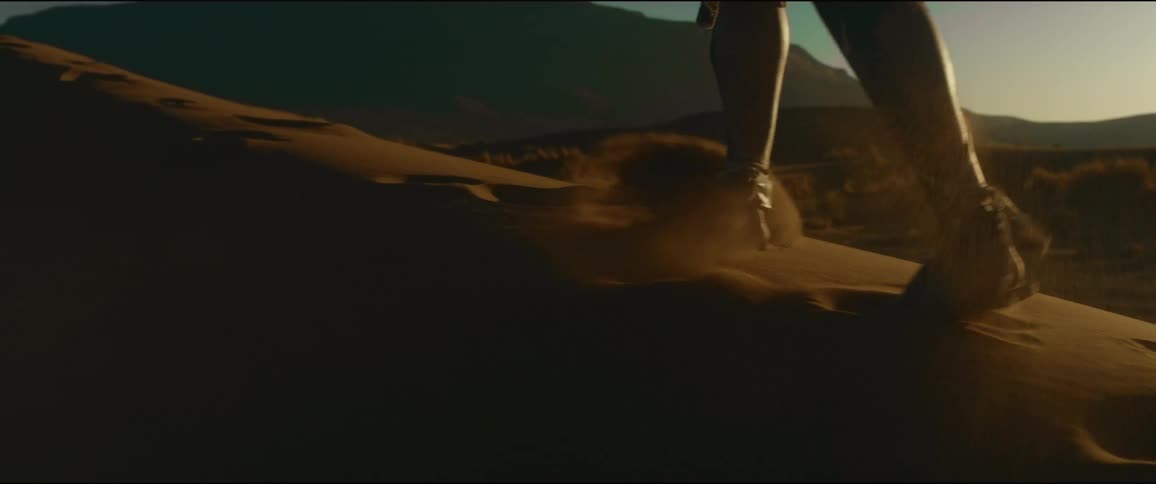 A man is trudging along in the sand of a dune in the desert