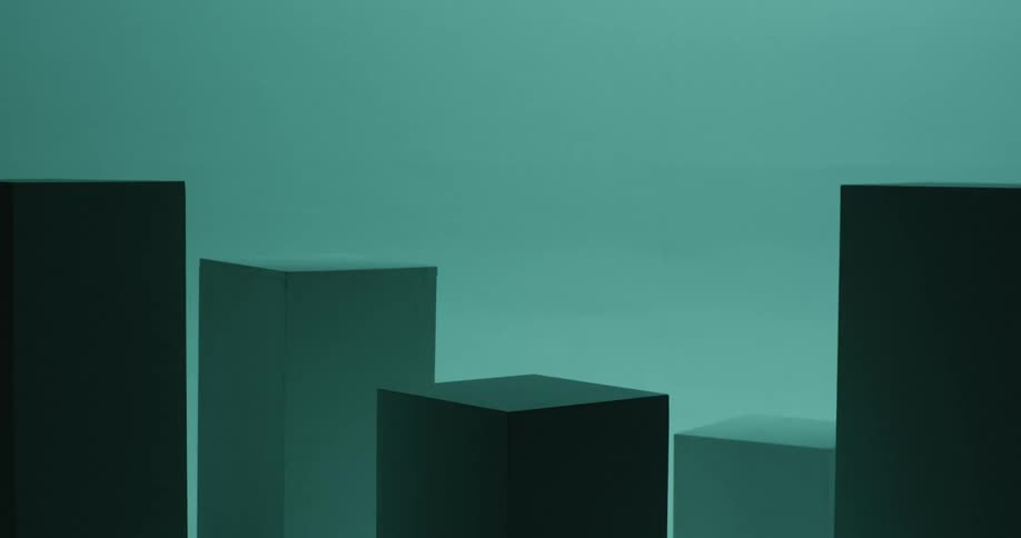 Rectangle shaped boxes are sitting on the floor of an empty room as turquoise color flashing lights shine on the boxes and walls