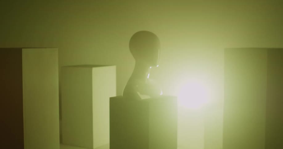 Lights flash on and off and change color in a room where a human bust sits on a pedestal