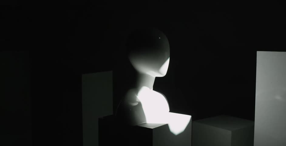 A bright light washes over a room where a bust of a human sits on a short pedestal