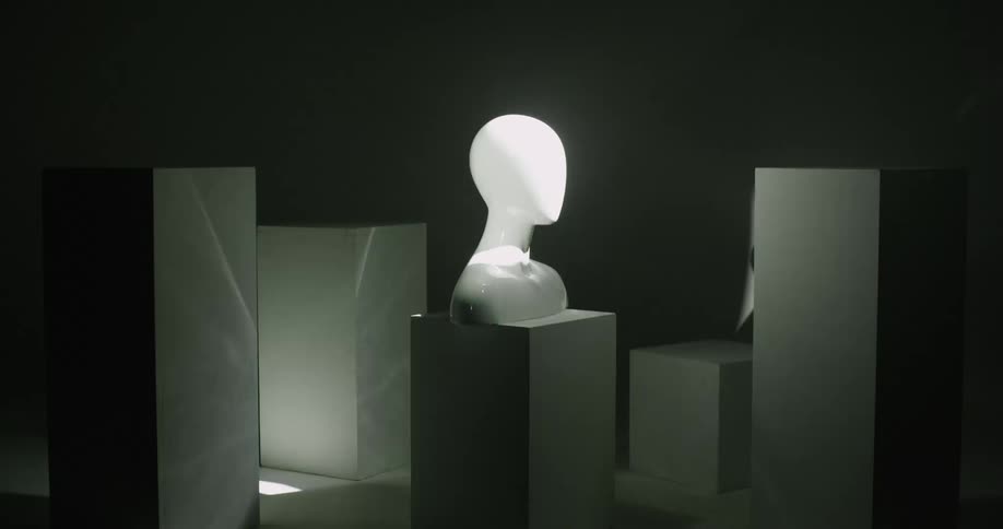 A human bust glows as it sits on a pedestal with flashing white lights