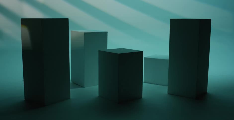 Rectangle shaped boxes are sitting on the floor of an empty room as flashing lights shine on the boxes and floor as well as the walls
