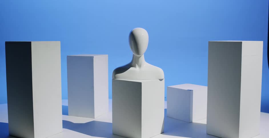 A mannequin bust sitting on a cube pedestal with colorful lights changing and glowing