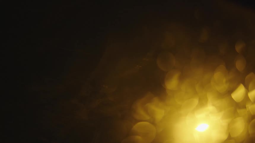 Glowing yellow and green light shimmer against black