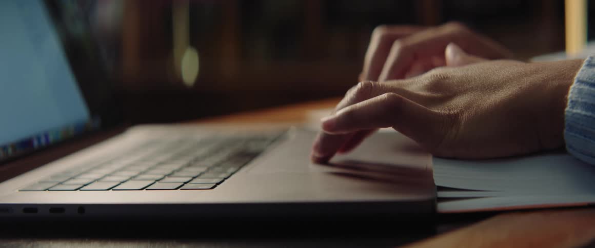 A girl is typing on a laptop computer and using her fingers to control the mouse