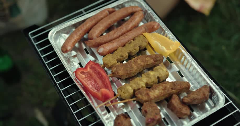 Peppers being added to bbq meat in tin pan outdoors