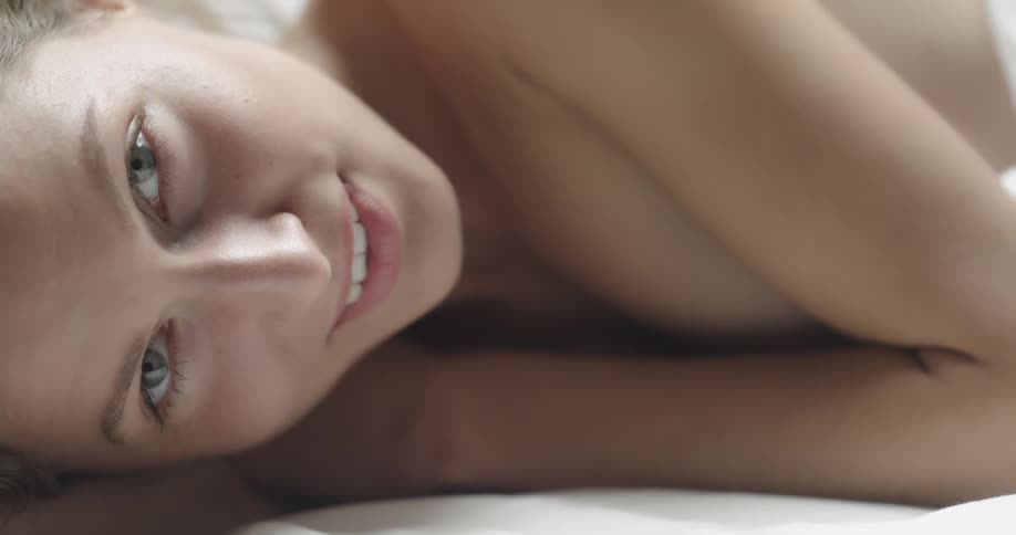 Topless female model lies down and smiles at camera