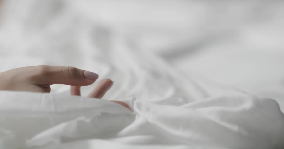 Hand grasps white fabric and pulls it across larger white fabric