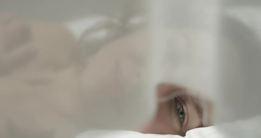 Close up of a womans face as she lies in bed