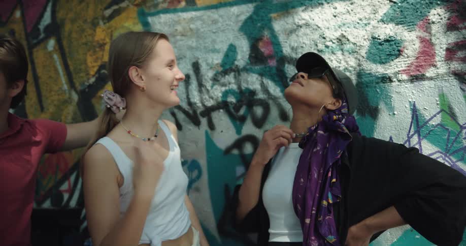 A group of young people stands around laughing and talking in a city