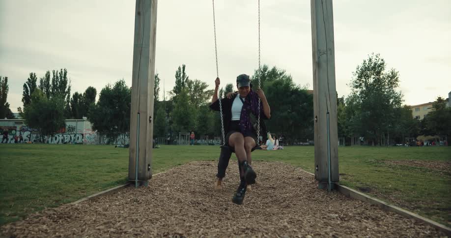 Two friends race to a swing in a park one gets on and the other pushes