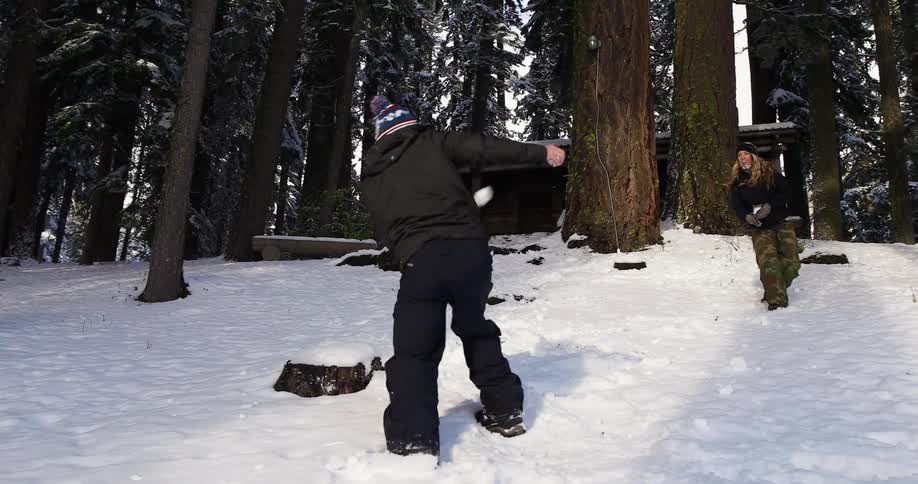 A group of people engage in a snowball fight in the woods