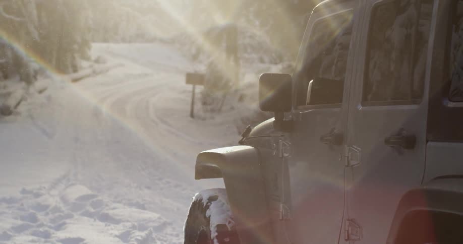 A jeep parked in the snow on a sunny day