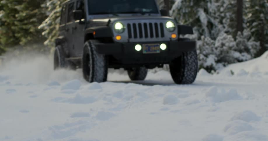 A jeep drives in the snow near some trees