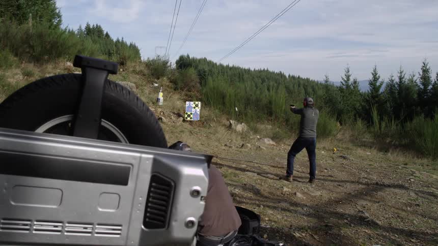 Man fires a gun at a target in the wilderness