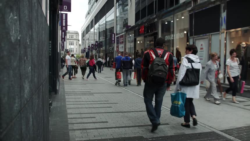 Pedestrians stroll down a shopping plaza during the day