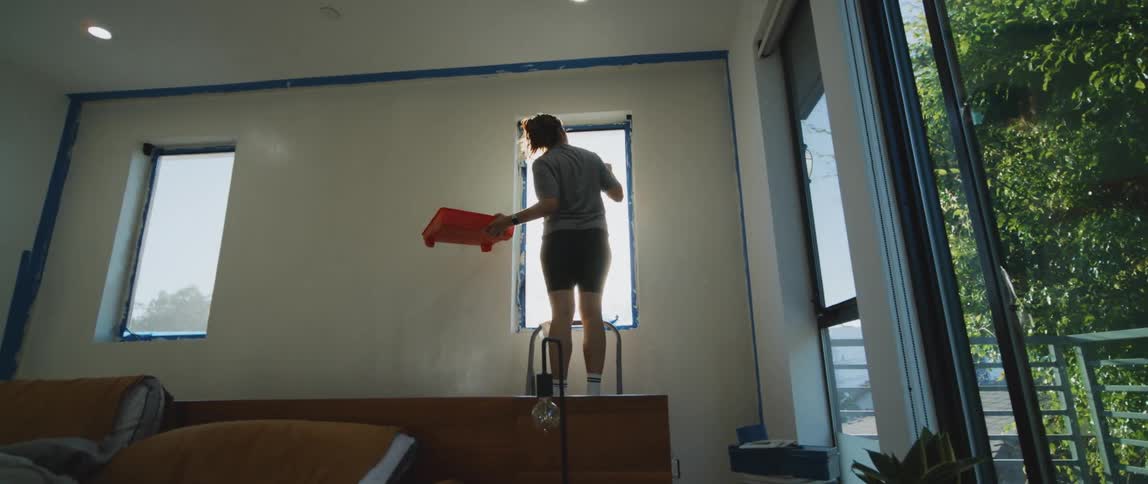 A woman paints a window in her house